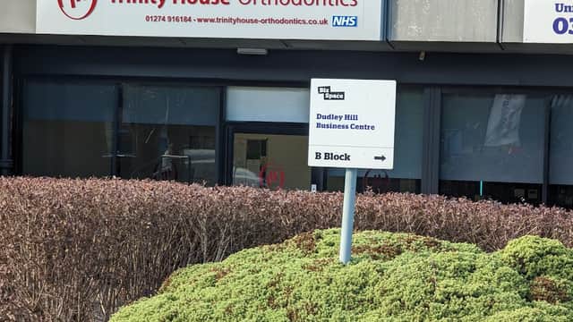 Sign for Trinity House Orthodontics with contact info, located in Dudley Hill Business Centre, surrounded by greenery.