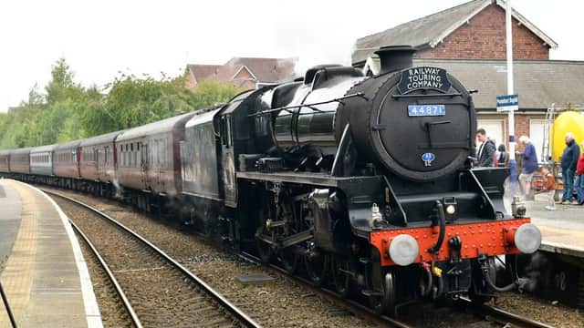 A steam locomotive at Pontefract Baghill station, with vintage carriages and a platform in a rural setting.