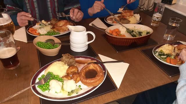 A table with plates of traditional British pub food, including roast dinner, vegetables, and drinks.