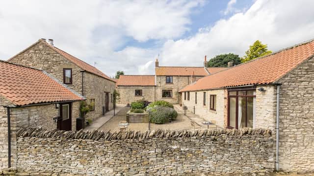 Charming stone cottages with red roofs and a landscaped courtyard, surrounded by a dry stone wall in Old Byland.