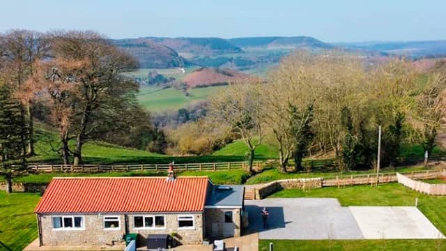 Luxury lodge with a red-tiled roof, surrounded by green fields and hills in Broxa, North Yorkshire.