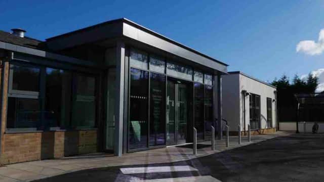 Entrance of Oaken Grove Community Centre featuring double doors, planters, benches, and a paved area.