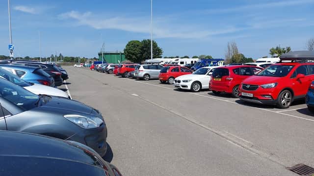 Pay & Display parking lot on Moorfield Road, featuring rows of parked cars in various colors under a clear blue sky.