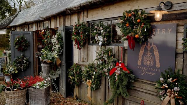 Charming floristry shop with festive wreaths, greenery, and seasonal decorations adorning wooden doors and walls.