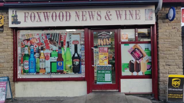 Foxwood Newsagents & Wine shopfront with colorful advertisements, drinks, and a sign stating "WE ARE OPEN."