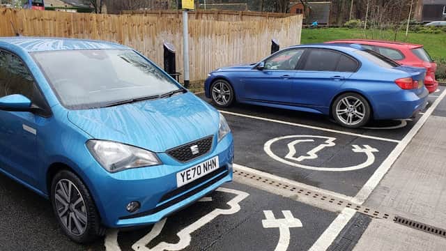 Two electric vehicles parked at a Pod Point Charging Station with designated charging spaces in Holme Valley, Yorkshire.