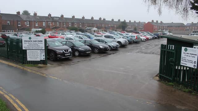 Pay & Display car park in Northallerton, lined with parked cars and residential buildings in the background.