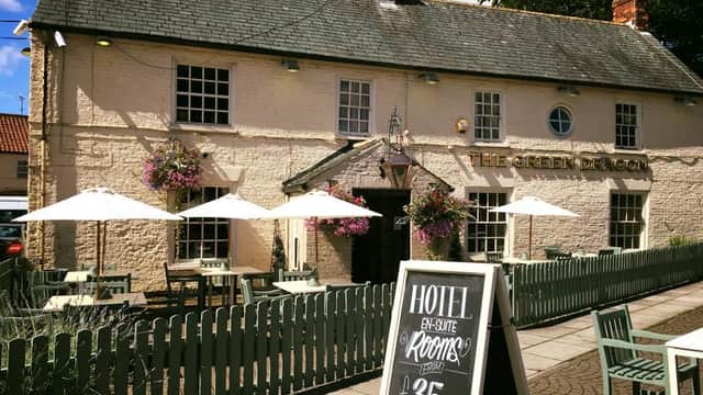 The Green Dragon pub with outdoor seating, parasols, and a sign advertising hotel rooms for £35.