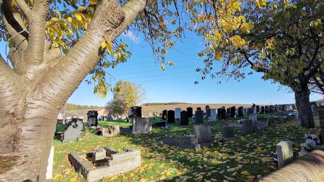 Wood Lane Burial Ground with gravestones, autumn leaves, and a clear blue sky in Treeton, Yorkshire.