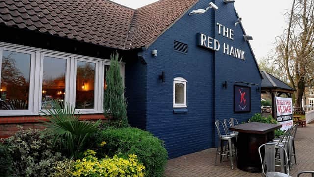 Exterior of The Red Hawk bar in Welton, Yorkshire, featuring a blue facade, outdoor seating, and greenery.