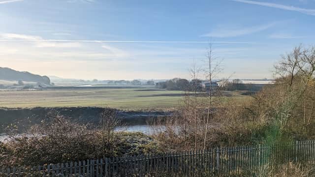 View of a serene landscape with fields and trees, under a clear blue sky near Mexborough Railway Station Car Park.