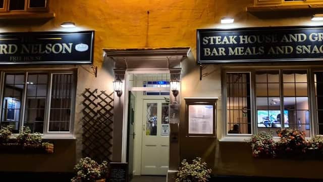 The Lord Nelson pub entrance with signage for steak house, grill, and bar meals, surrounded by flower boxes.