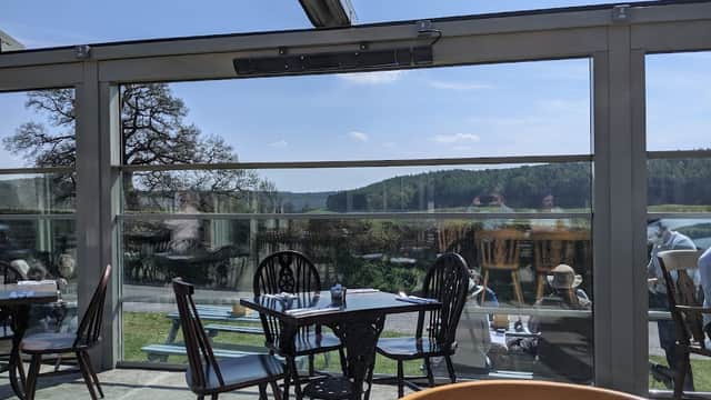 Bright interior of The Stone Trough Inn with tables and chairs, large windows showcasing a scenic view of greenery.