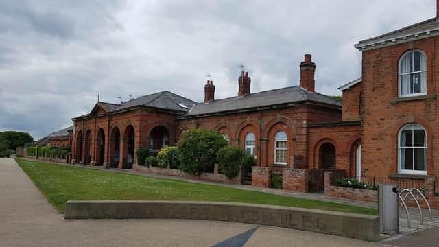 Sands Lane parking area with brick buildings, arched entrances, and a stone sign for Doncaster 15 miles ahead.