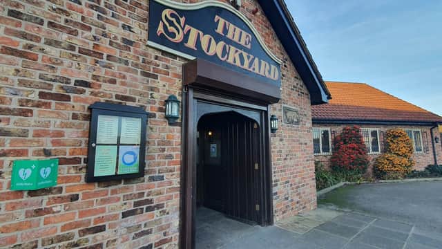 Entrance to The Stockyard Truckstop with brick exterior, menu board, and colorful plants by the doorway.