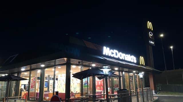 McDonald's restaurant at night, featuring outdoor seating, bright signage, and illuminated interior.