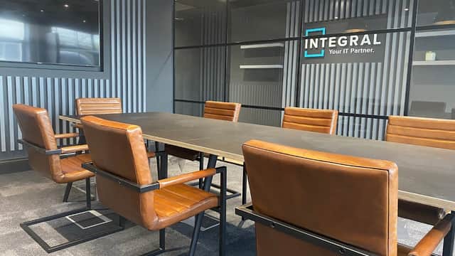Modern conference room with a large black table, brown leather chairs, and a glass wall displaying the "INTEGRAL" logo.
