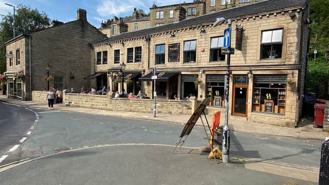 St. Georges Square car park with a stone building, outdoor seating, and pedestrians in Chiserley, Yorkshire.