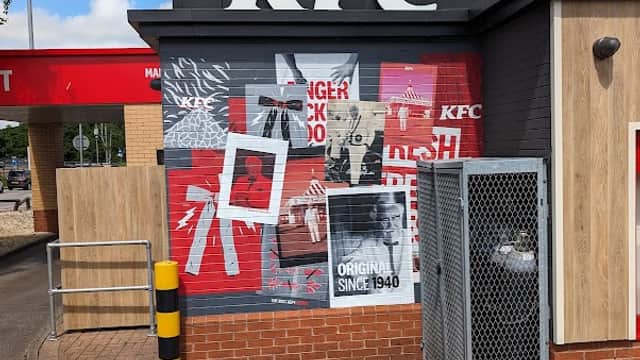KFC storefront with bold red and black signage, featuring posters and a drive-thru area in Keighley Retail Park.