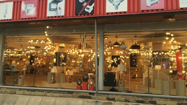 Brightly lit homeware store showcasing various light fixtures and lamps behind large glass windows.