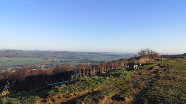 Scenic view from East Chevin Quarry Car Park, overlooking green hills and valleys under a clear blue sky.