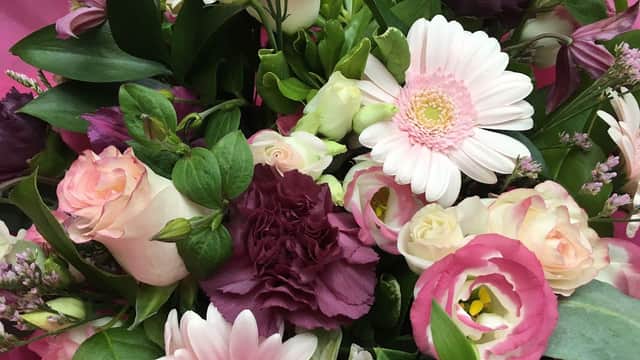 A vibrant bouquet featuring pink and white flowers, including gerberas, roses, and lush greenery.