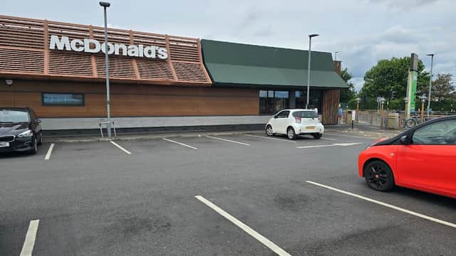 McDonald's restaurant exterior with a parking lot, featuring a wooden facade and green awning.