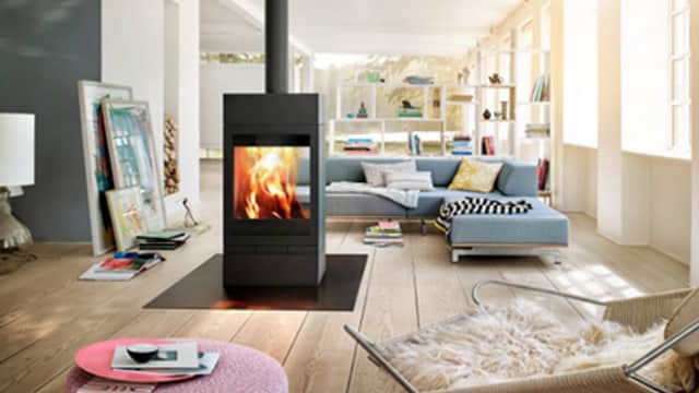 Modern living room featuring a black fireplace, cozy blue sofa, and stylish decor with natural light streaming in.