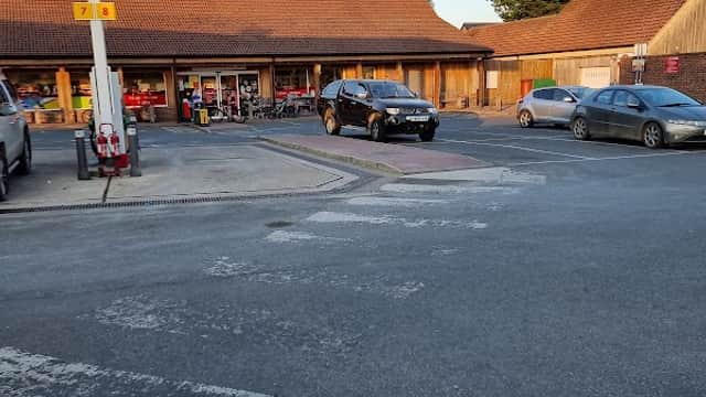 SPAR Manor Garage features a shop with a wooden facade, parked cars, and a clear blue sky above.
