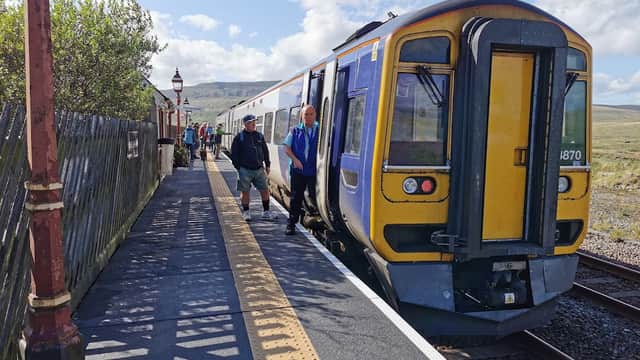 Ribblehead Visitor Centre with passengers disembarking from a train at a scenic Yorkshire station.