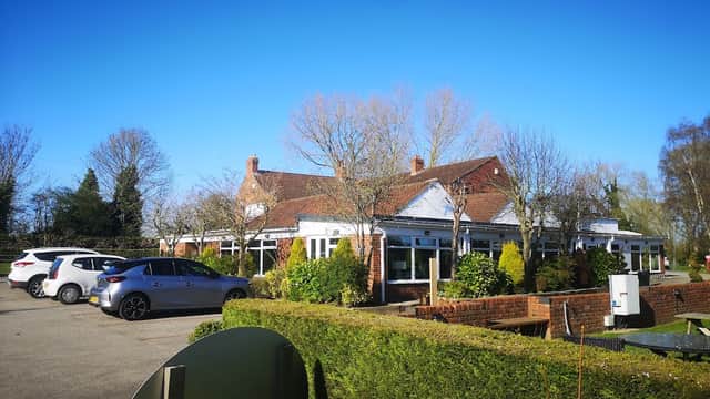 Cawood Park features a charming building surrounded by greenery and parked cars under a clear blue sky.