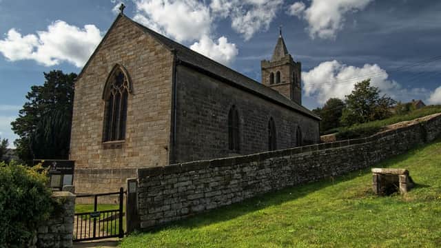 St Thomas' Church in Glaisdale, Yorkshire, features stone walls, a tall tower, and lush greenery surrounding it.