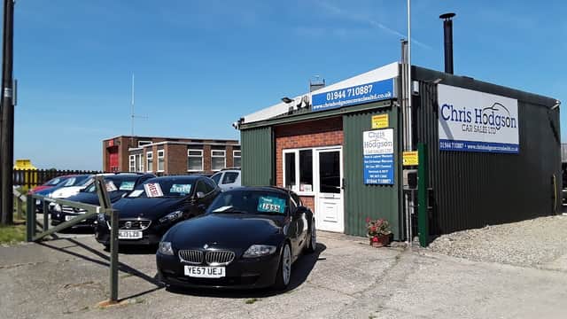 Chris Hodgson Car Sales Ltd shop front in Sherburn, Yorkshire, with parked cars and a clear blue sky.