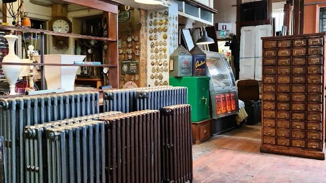 Antique shop interior featuring vintage radiators, wooden cabinets, signage, and a retro vending machine.