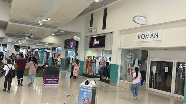 Interior view of St Johns Centre, featuring shops, shoppers, and a modern ceiling design with overhead lighting.