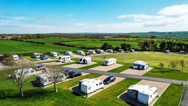 Caravan park with neatly arranged caravans on grassy plots, surrounded by green fields and blue sky in Lebberston, Yorkshire.