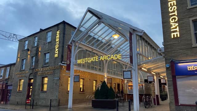 Westgate Arcade entrance featuring glass roof, illuminated signage, and surrounding brick buildings in Halifax, Yorkshire.