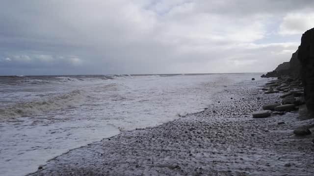 Stormy sea waves crashing on a pebbled shore under a cloudy sky at Skirlington Hornsea Road, Atwick, Yorkshire.