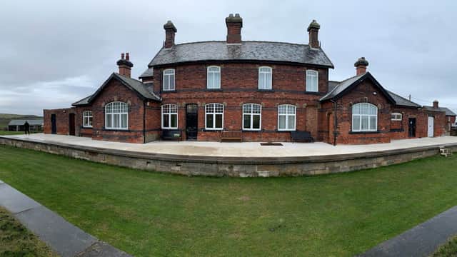 Historic red brick building with multiple chimneys, large windows, and a grassy area in Kettleness, Yorkshire.