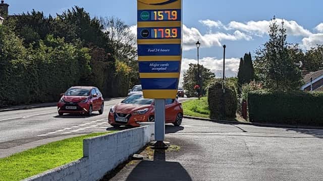 Crakehall Petrol Station sign displaying fuel prices, with cars parked nearby and greenery in the background.