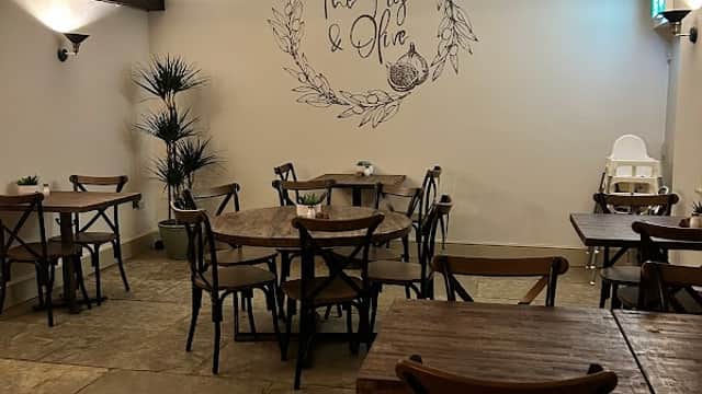 Cozy interior of The Fig & Olive with wooden tables, chairs, and a decorative wall mural in Womersley, Yorkshire.