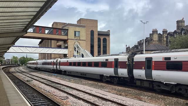 Train tracks with parked trains at Harrogate station, surrounded by modern and traditional buildings under a cloudy sky.