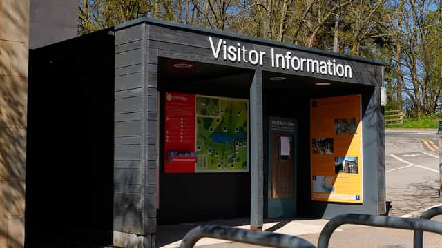 Visitor information center with a map, signage, and bike racks outside in a wooded area.