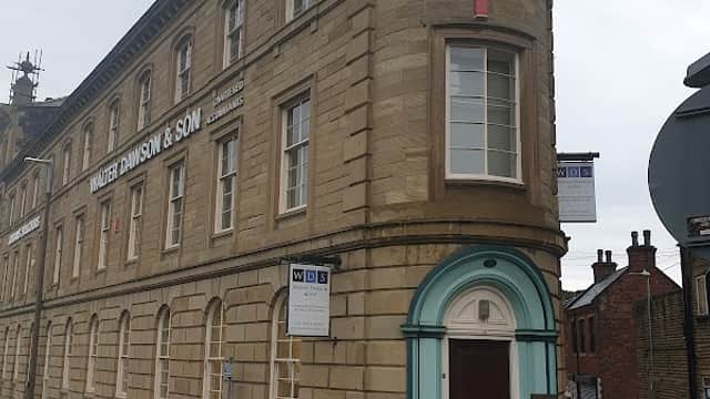 Walter Dawson & Son Car Park in Dewsbury, featuring a historic stone building with a curved corner and signage.