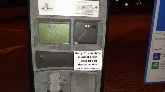 Pay & Display parking meter with multiple out-of-order notices and instructions, set in a car park at night.
