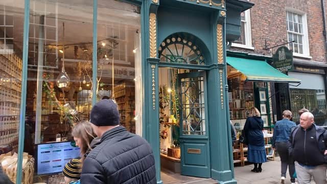 Quaint bookshop entrance with green door, large windows, and people browsing outside in a charming York street.