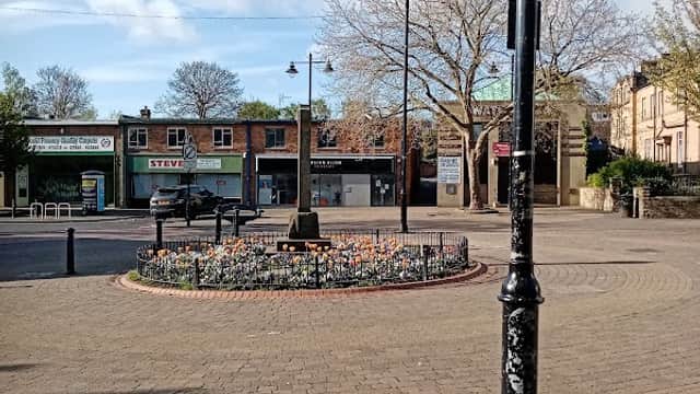 Biscay Way Car Park features a flower bed, lampposts, and storefronts under a partly cloudy sky in Wath upon Dearne.