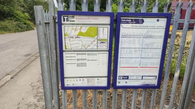 Two information boards at Woodhouse Station Car Park displaying a map and train schedule, surrounded by greenery.