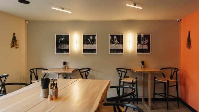 Stylish café interior with wooden tables, black chairs, and framed black-and-white photos on the wall.