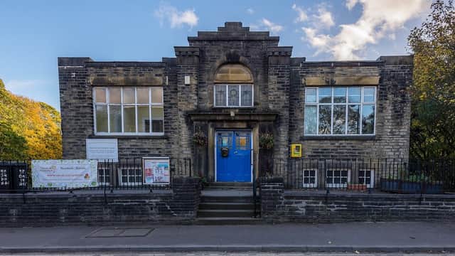Luddenden Foot Community Centre features a stone facade, large windows, and a blue door, surrounded by trees.